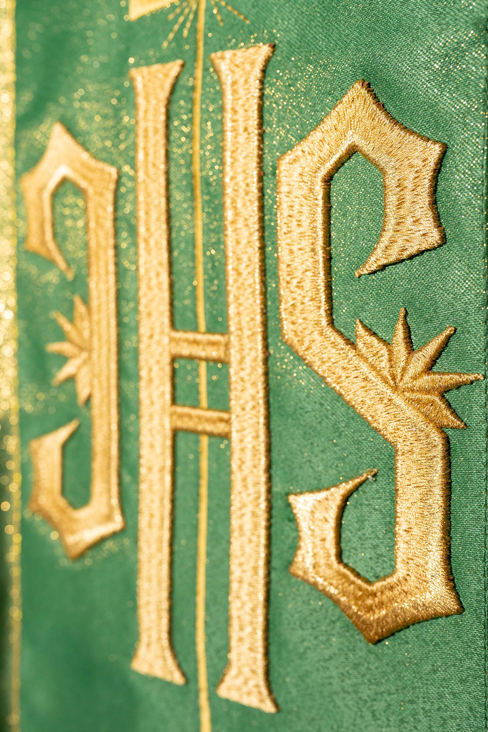 Richly decorated green chasuble with golden motifs and a wide IHS band