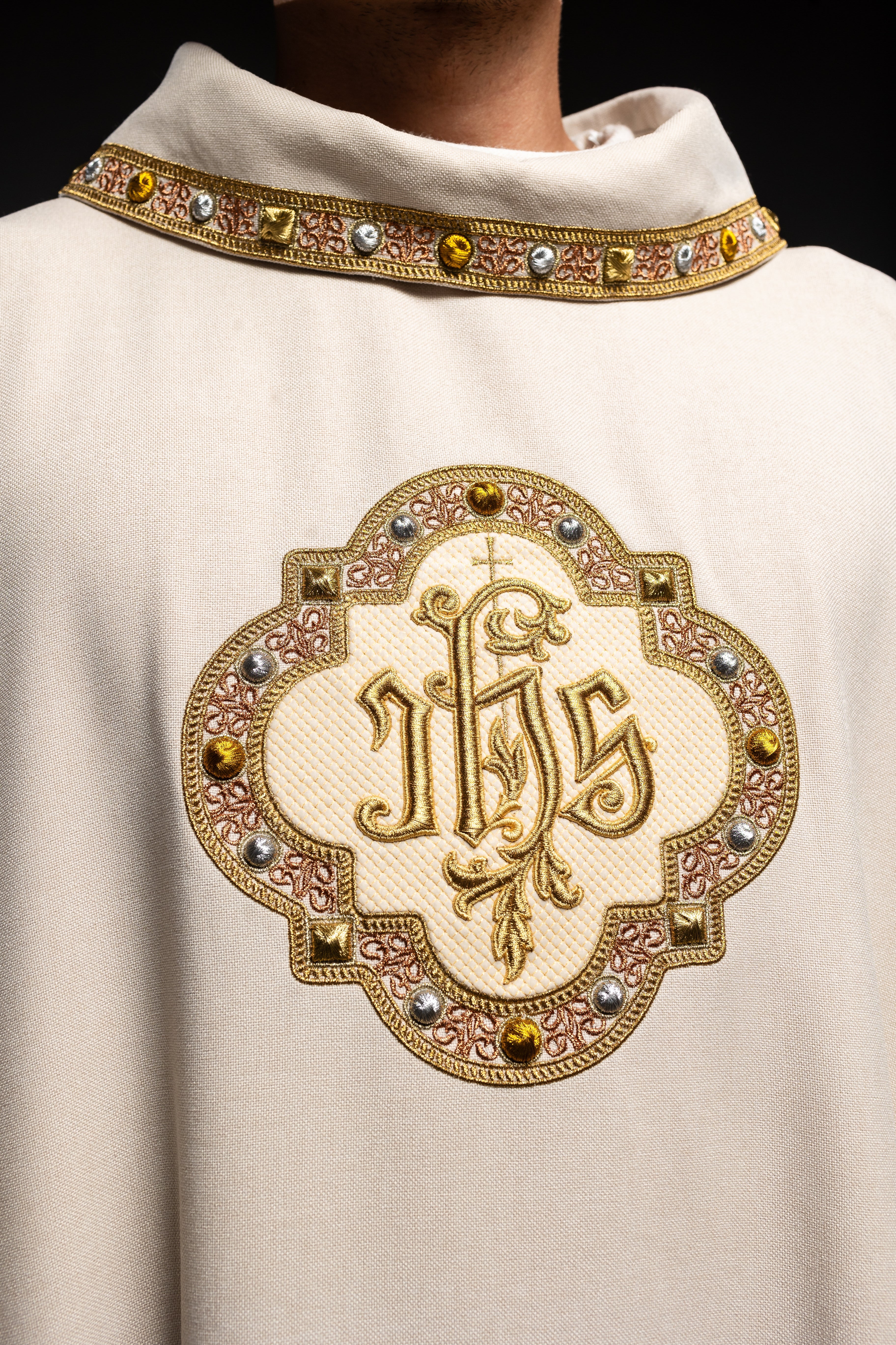 Cream colored chasuble with classic JHS symbol and colorful collar